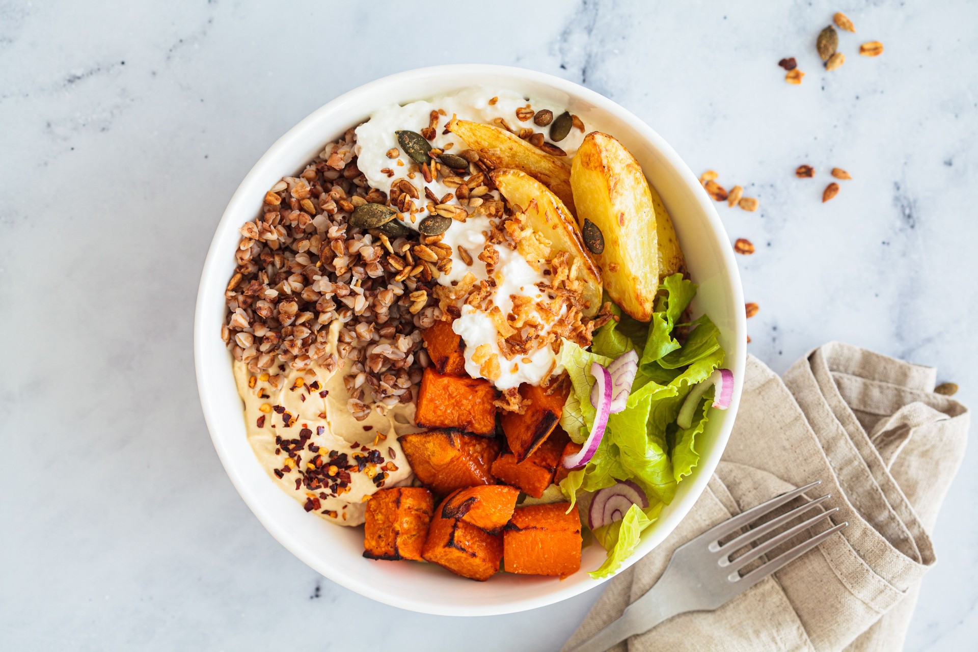 Vegetarian buddha bowl with buckwheat, cottage cheese, hummus and baked potatoes. Balanced food concept.